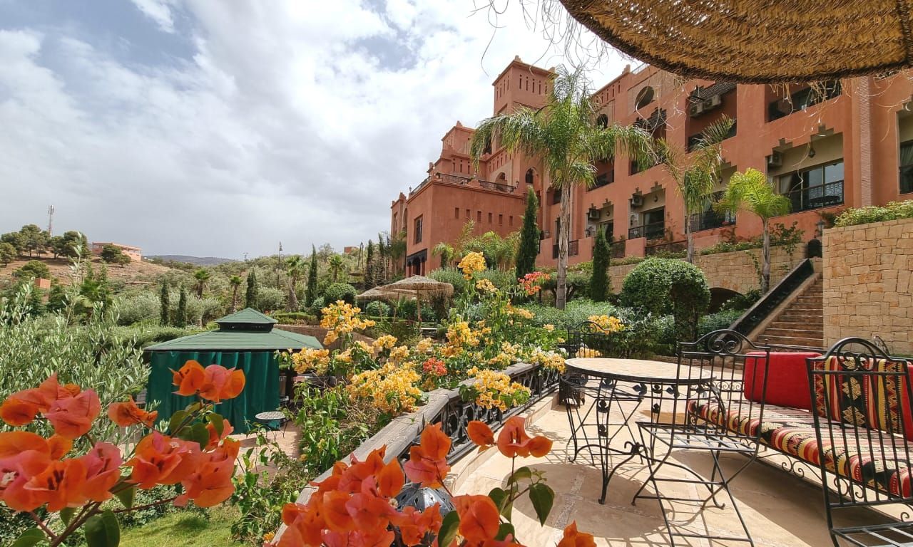 A courtyard with a garden, outdoor seating, and a building with multiple balconies.