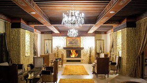 Una sala de estar tradicional con chimenea, techo ornamentado y muebles clásicos.