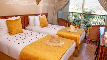 A hotel room with two beds, a balcony with a table and chairs, and a view of the landscape.