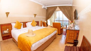 A hotel room with a large bed, a desk, a chair, and a balcony view.