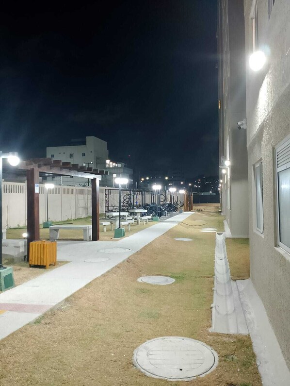 A nighttime outdoor area with a pathway, benches, and a building in the background. - Apê Pé na Areia-Vista Mar (Fortaleza)