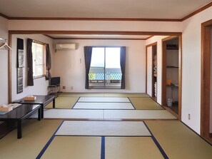 Une pièce avec des tatamis, un bureau, une chaise, une armoire et une fenêtre donnant sur un beau paysage.