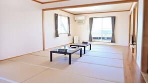 A room with tatami flooring, two tatami mats, a sliding door, a window with curtains, and a small table with a basket. - B B Dylan (Otsu)
