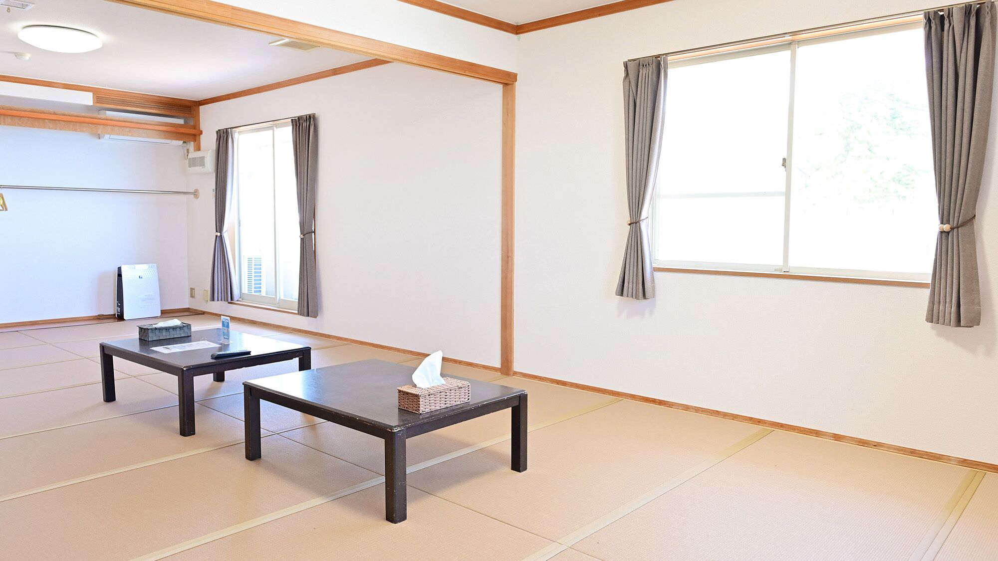A room with two tables, a window with curtains, and a white wall.