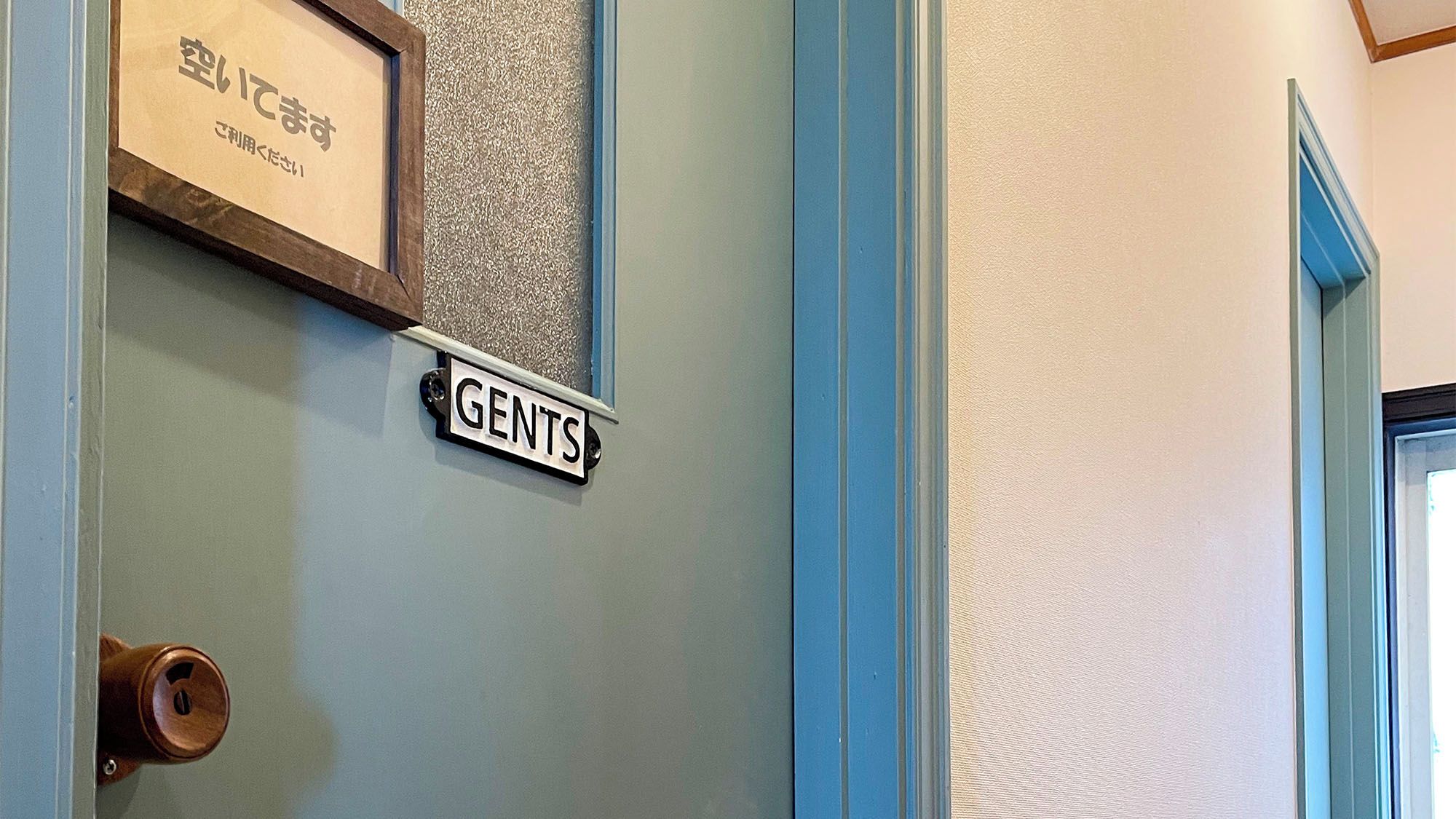 A door with a sign labeled 'GENTS' and a framed sign above it.