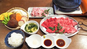 A table with various food items including rice, meat, vegetables, and a hot pot.