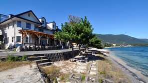 A coastal building with a terrace, a stone wall, and a view of the sea. - B B Dylan (Otsu)
