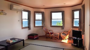 Een kamer met uitzicht op zee, een televisie en een futonbed.
