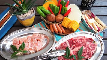 A table with various food items including raw chicken, steak, vegetables, and sausages.