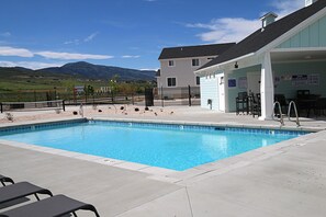 Ein Schwimmbecken mit Bergblick, eine überdachte Terrasse mit Sitzgelegenheiten und ein eingezäunter Bereich.