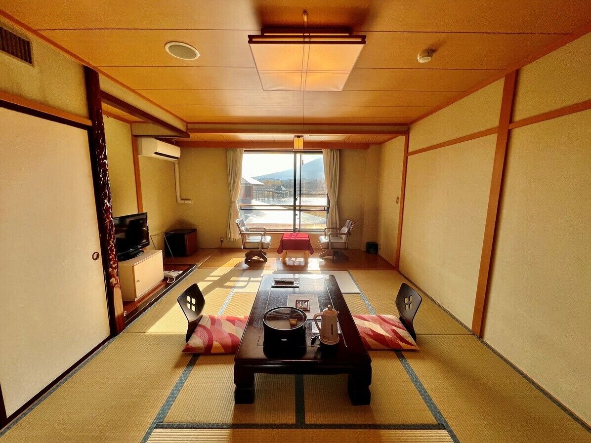 Habitació japonesa tradicional amb fons de tatami, una taula baixa i un televisor sobre un moble.