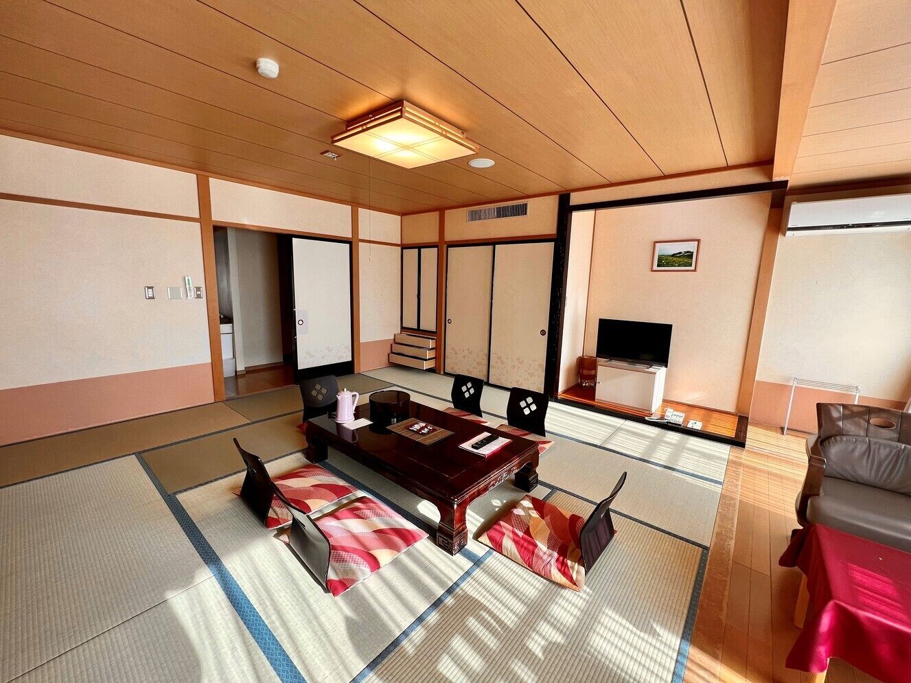 Habitació japonesa tradicional amb sòls de tatami, una taula de fusta baixa i un sofà.