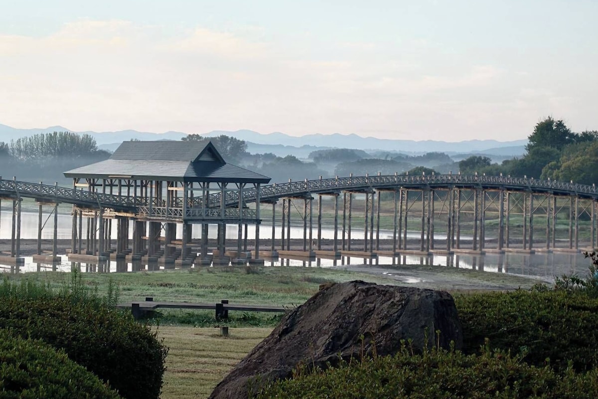 A wooden pier extending over a body of water with a covered structure at the end.