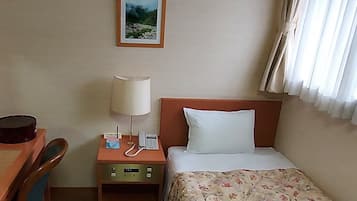A hotel room with a bed, a desk, a nightstand with a lamp, a telephone, and a painting on the wall.