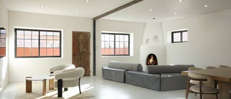 A spacious living room with a fireplace, a sofa, a coffee table, and a dining area with chairs.