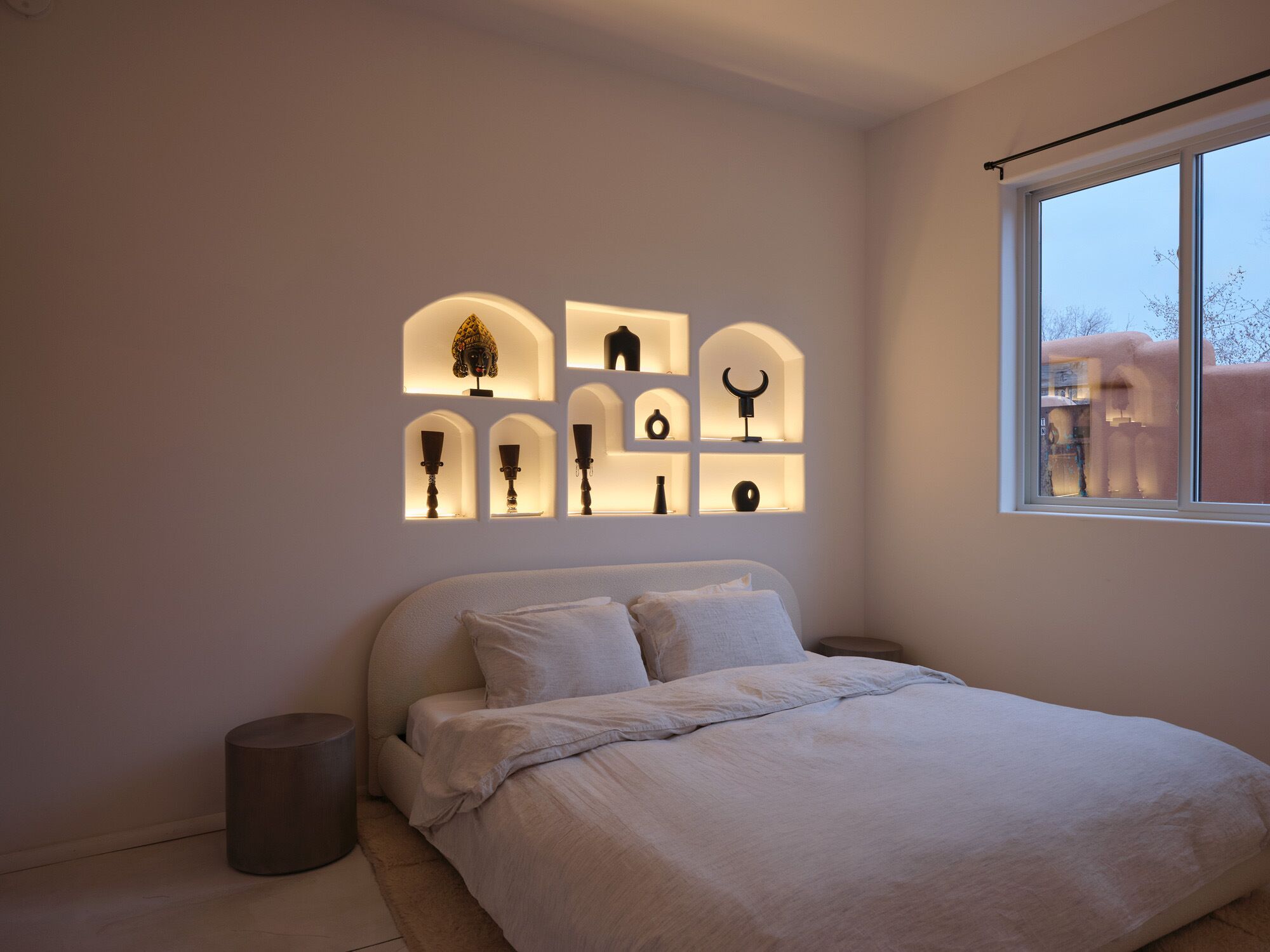 A bedroom with a bed, a bedside table, and a window.