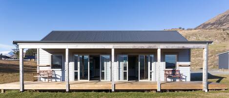 A modern house with a covered porch, large glass doors, and a metal roof.