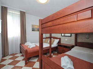 A hotel room with two wooden beds, a small bedside table, a nightstand, and a checkered floor. - Wohnung mit Waschmaschine und Geschirrspüler by Interhome (Bigova)