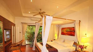 Ein Zimmer mit einem Bett, einem Fernseher, einem Deckenventilator und einem Fenster mit Vorhängen.