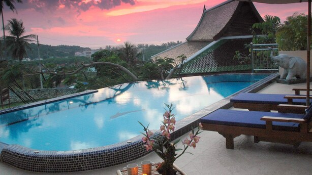 Ein Pool mit gefliestem Rand, Liegestühlen und einer Zierpflanze.