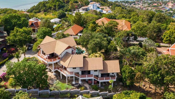 Zona residencial costera con casas rodeadas de exuberante vegetación y vista al mar.