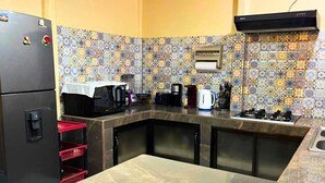 Eine kompakte Küche mit Kühlschrank, Mikrowelle, Kaffeemaschine und Gaskochfeld.