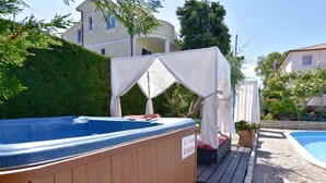 Un bain à remous entouré d’une structure en bois, un espace salon couvert et une piscine.