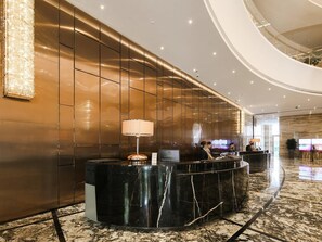 A modern hotel lobby with a marble reception desk, a large chandelier, and a curved ceiling. - Guangzhou Vaperse Hotel Zhujiang Newtown (Guangzhou)