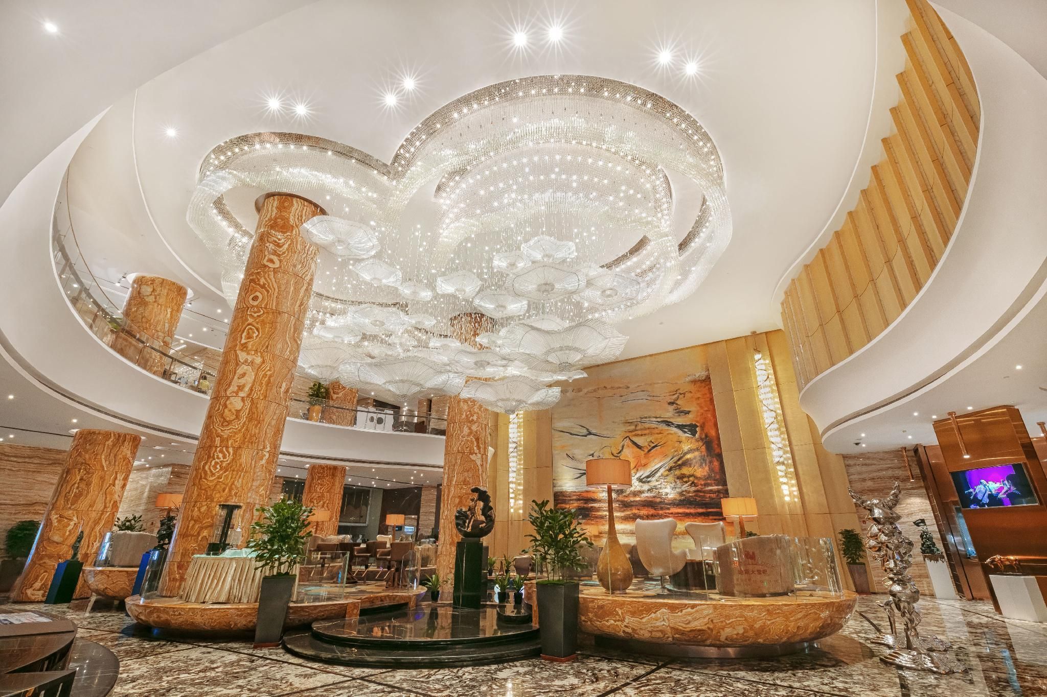 Un hall d’entrée spacieux, agrémenté d’un imposant lustre, de colonnes en marbre et d’une grande fresque murale.