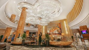 A spacious lobby with a grand chandelier, marble columns, and a large mural. - Guangzhou Vaperse Hotel Zhujiang Newtown (Guangzhou)