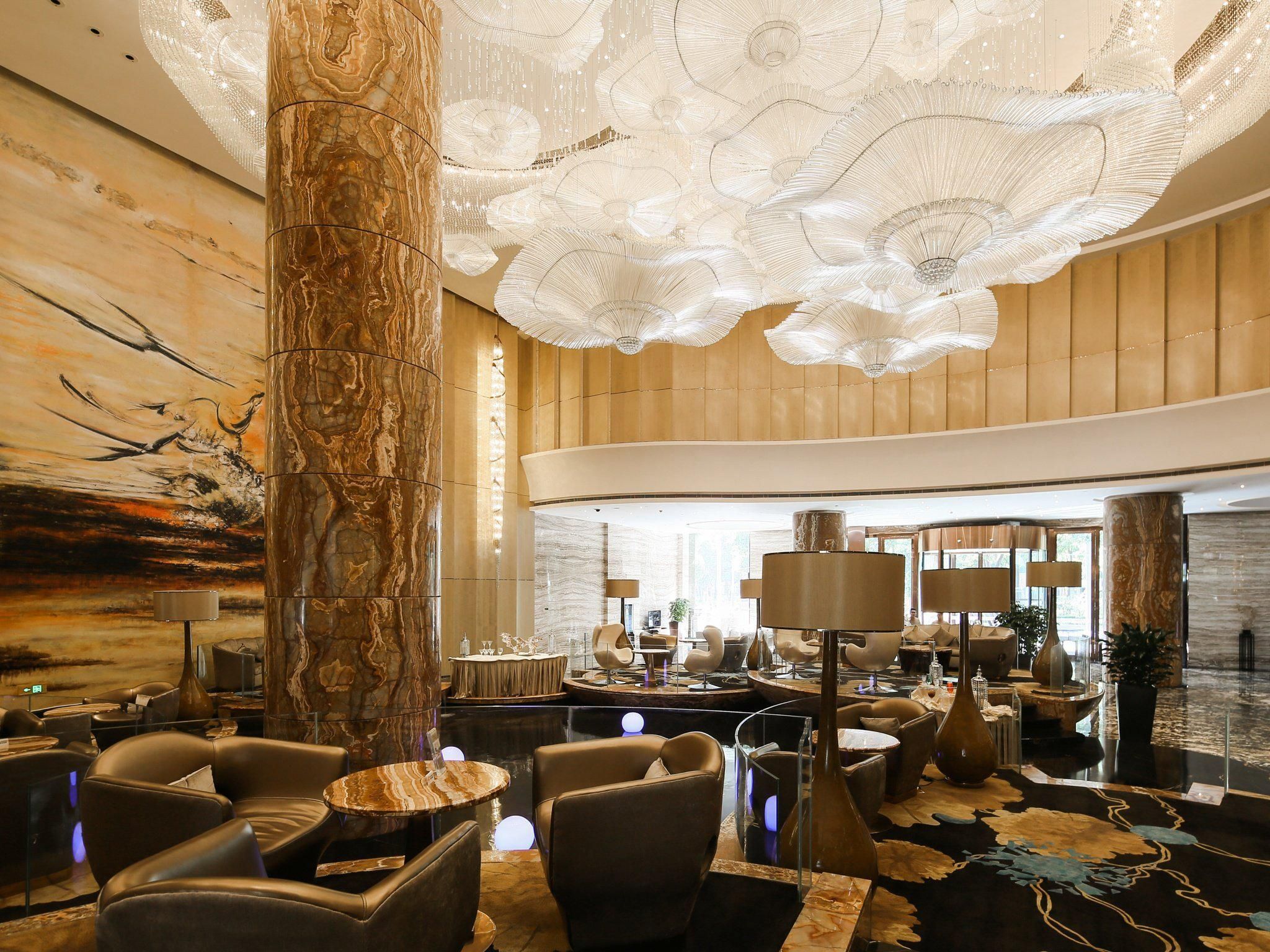 A spacious lobby with a high ceiling, marble columns, and modern seating areas.