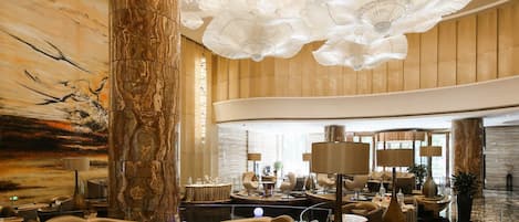 A spacious lobby with a high ceiling, marble columns, and modern seating areas.