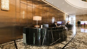 A modern hotel lobby with a marble reception desk, a large chandelier, and a curved ceiling. - Guangzhou Vaperse Hotel Zhujiang Newtown (Guangzhou)