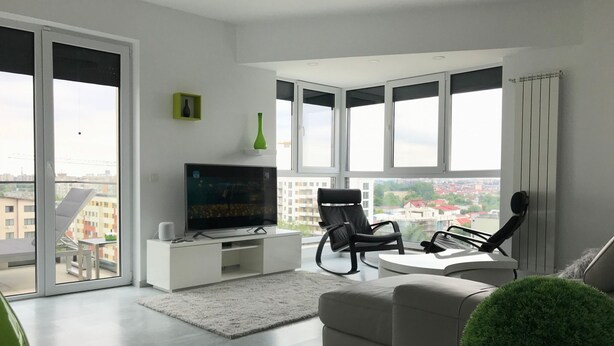 A modern living room with a flat-screen TV, a sofa, a coffee table, and a view of the city through large windows. - Luxus-Residenz Westpark 2 by Interhome (Bucuresti)