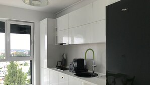 A modern kitchen with white cabinets, a black refrigerator, a built-in oven, and a window with a city view. - Luxus-Residenz Westpark 2 by Interhome (Bucuresti)