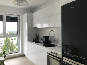 A modern kitchen with white cabinets, a black refrigerator, a built-in oven, and a window with a city view. - Luxus-Residenz Westpark 2 by Interhome (Bucuresti)