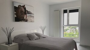 A modern bedroom with a bed, a nightstand, a window with curtains, and a painting on the wall. - Luxus-Residenz Westpark 2 by Interhome (Bucuresti)