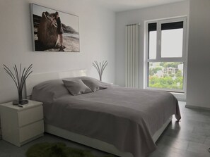 A modern bedroom with a bed, a nightstand, a window with curtains, and a painting on the wall. - Luxus-Residenz Westpark 2 by Interhome (Bucuresti)