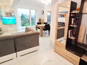 A modern living room with a sofa, a TV, a dining area with chairs, and a wooden bookshelf. - Familienvilla mit Meerblick "Arode Villa Ovid" by Interhome (Baltschik)