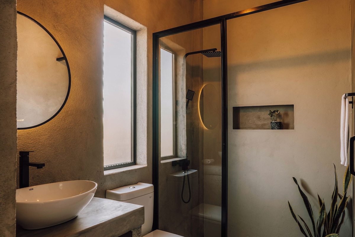 A modern bathroom with a large sink, toilet, and glass shower enclosure.