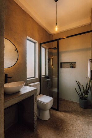 Ein modernes Badezimmer mit einem großzügigen Waschbecken, Toilette und einer Duschkabine aus Glas.