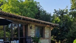 Un espace de restauration en plein air avec une table recouverte d’une nappe blanche, entourée de verdure et avec un bâtiment en pierre en arrière-plan.