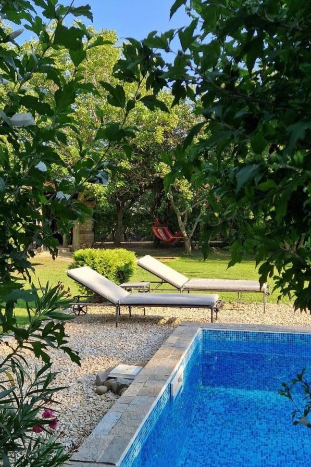 A swimming pool with lounge chairs and a garden area.