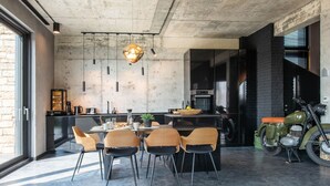 A modern kitchen with a dining area, featuring a concrete ceiling, a large window, and a vintage motorcycle. - Exklusive Villa mit Swimmingpool und Whirlpool by Interhome (Varna)
