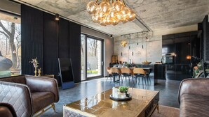 A modern living room with leather sofas, a glass coffee table, and a dining area with a kitchen in the background. - Exklusive Villa mit Swimmingpool und Whirlpool by Interhome (Varna)