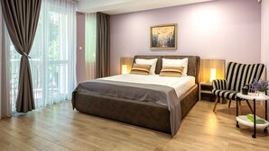 Une chambre d’hôtel moderne avec un grand lit, une chaise, une petite table et un tableau au mur.