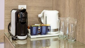 Une machine à café, une bouilloire et deux tasses sur un plan de travail.