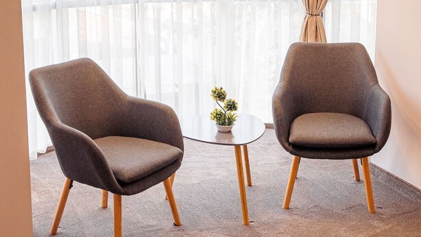 Una habitación con dos sillones, una pequeña mesa redonda y una planta en maceta.