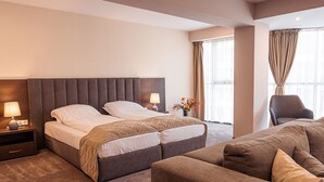 Habitación de hotel con una cama grande, un sofá, una silla y una mesita de noche con lámpara.