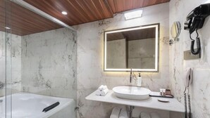 A modern bathroom with a marble wall, a large mirror, a sink, a bathtub, and a telephone. - Clarks Inn Suites Hyderabad (Hyderabad)